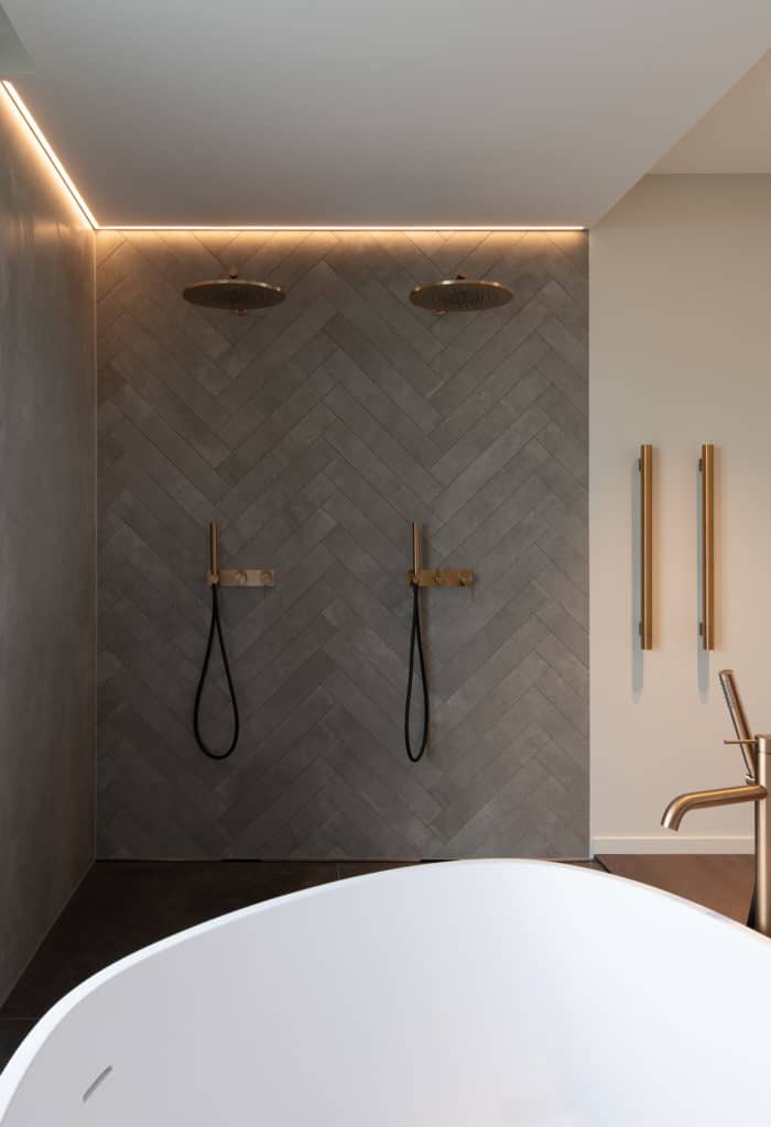 Douche italienne double dans salle de bain design et chic. Carrelage avec carreaux posé en chevron.