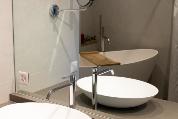 Mobilier de salle de bains en bois et lavabo blanc pour une salle de bain rénovée à Lutry.