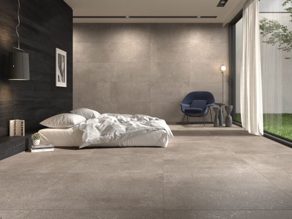 Salle à coucher avec sol en carrelage imitation pierre, lit blanc et mur en carrelage Loft