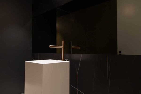 Lavabo design blanc dans toilettes avec des murs en carrelage imitation marbre noire