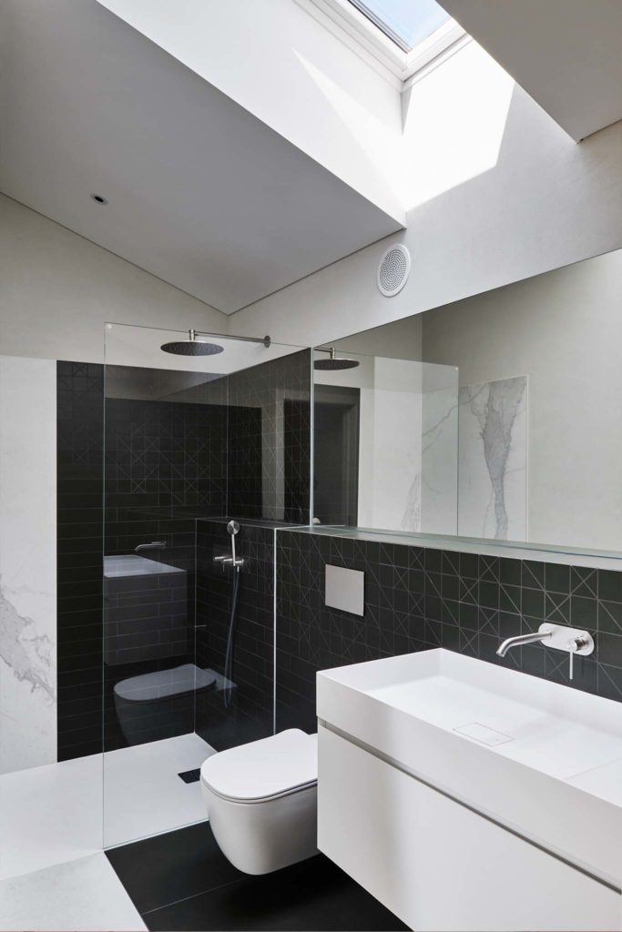 Carrelage dans une salle de bains design, douche italienne avec carrelage imitation marbre. Velux offrant une lumière naturelle