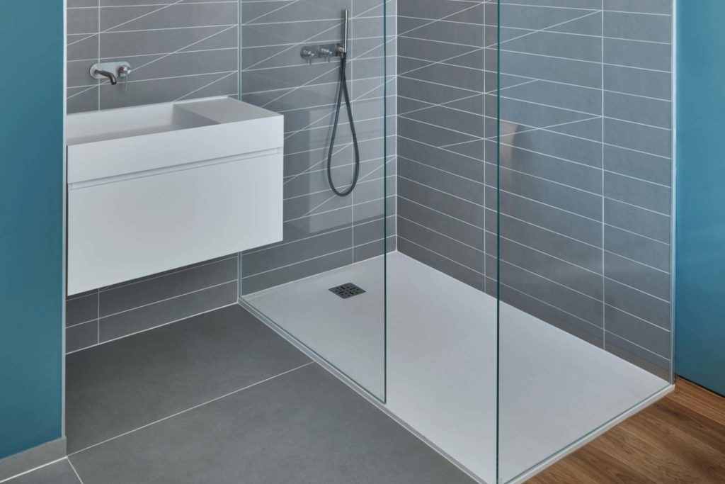 Salle de bains avec douche italienne en carrelage gris, baies vitrées pour protéger 