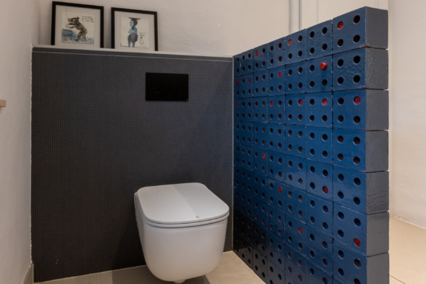 Toilettes dans salle de bains rénovées avec mur en brique bleu pour cacher le wc