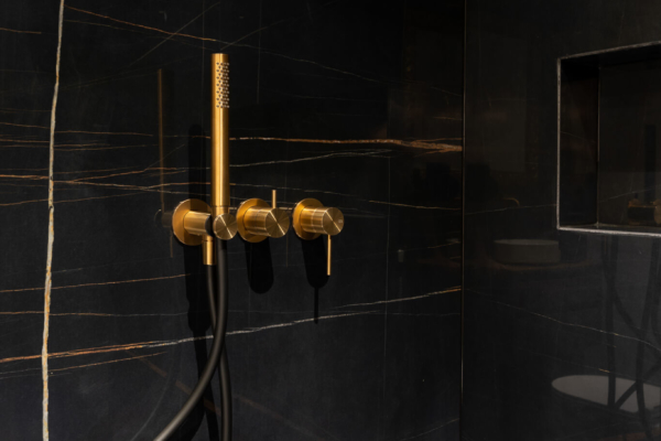 Robinets dorés de douche italienne avec carrelage imitation marbre noire