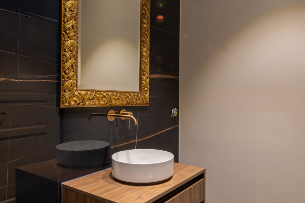 Miroirs et robinets dorés, meuble en bois pour lavabo dans salle de bains avec carrelage imitation marbre noire
