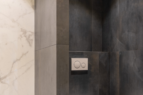 Separations entre les toilettes et la douche. Carrelage imitation marbre blanc contrastant avec une carrelage imitation béton noir.