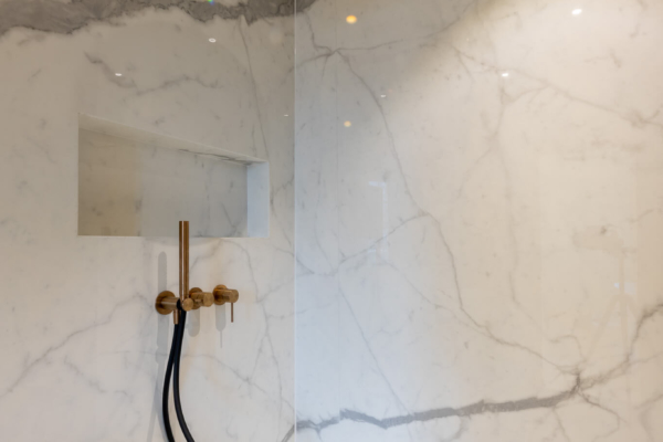 Gros plan sur la douche italienne imitation marbre et robinetterie dorées
