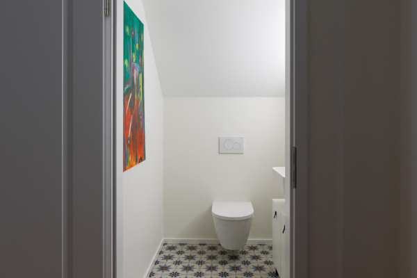 Toilettes avec wc blanc carrelage avec motif au sol et peinture au mur