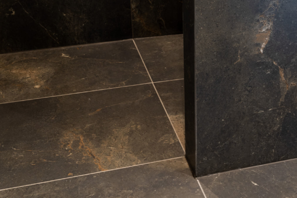 Détails de carrelage imitation pierre noir au sol, douche italienne avec mur de séparation
