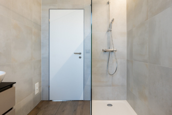 Douche italienne dans salle de bains avec carrelage imitation parquet au sol et carrelage gris au mur