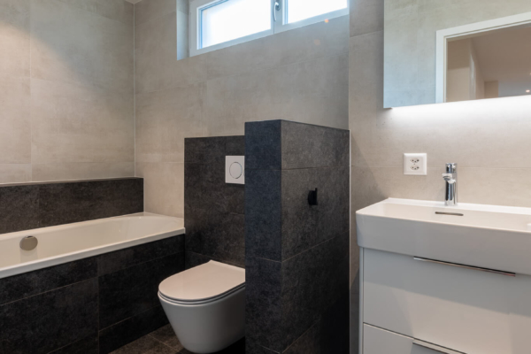 Salle de bains avec baignoire WC et lavabo, carrelage noir et gris