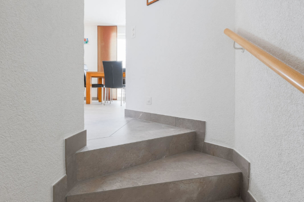 Haut d'escalier avec carrelage gris imitation pierre et vue sur séjour