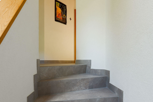 Haut d'escalier avec carrelage gris imitation pierre et vue sur hall
