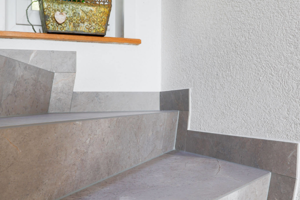 Détail d'escalier avec carrelage gris imitation pierre dans un maison rénovée à Epalinges